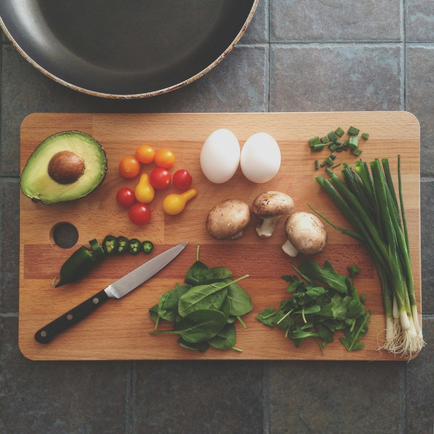 A pan mid-cook on the stove: fresh ingredients, herbs and oil in the heat.